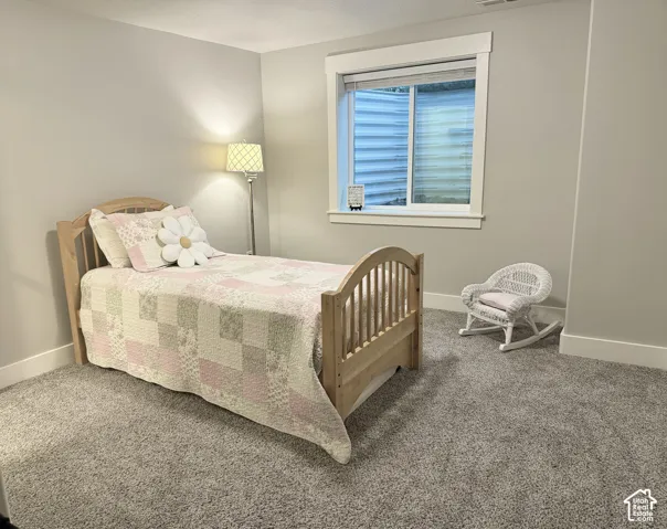 Neutral-toned room featuring wall-to-wall carpeting, window with corrugated metal window well, and crisp white trim