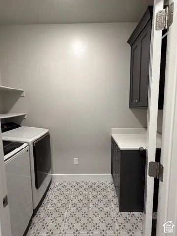 Laundry room featuring dark-finish custom cabinetry, white countertop surfaces, patterned floor tile, and wall-mounted shelving