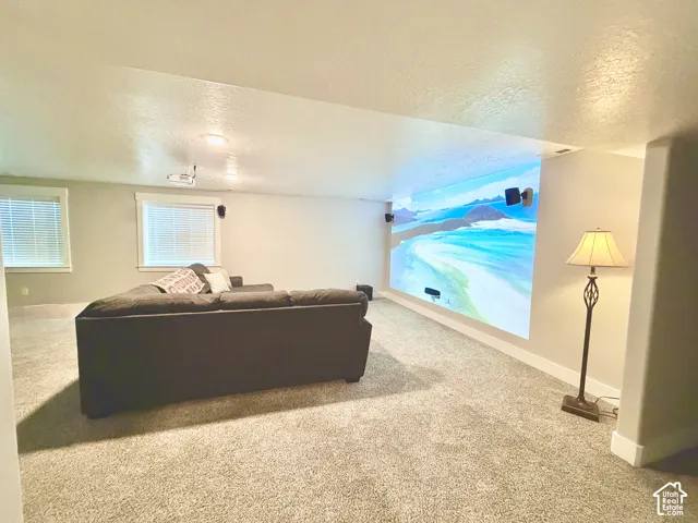 Spacious area featuring wall-to-wall carpeting, dual windows with horizontal blinds, a ceiling-mounted projector, and integrated wall-mounted speakers