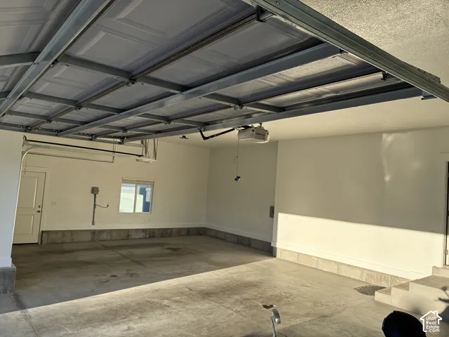 Multi-car garage featuring a concrete floor, finished interior walls, an automated door opener system, and a side-entry door