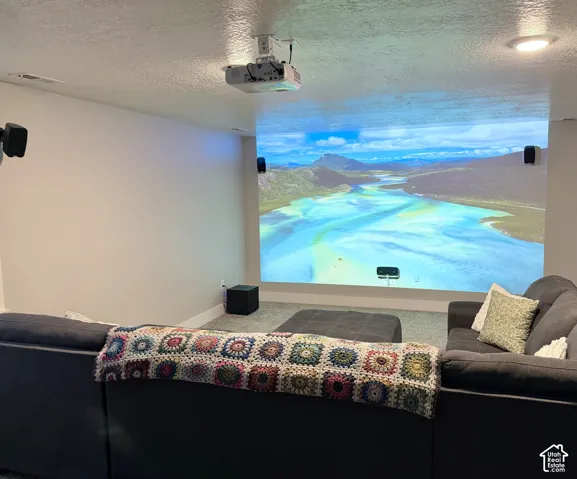 Media room featuring a ceiling-mounted projector, wall-mounted surround sound speakers, and recessed lighting