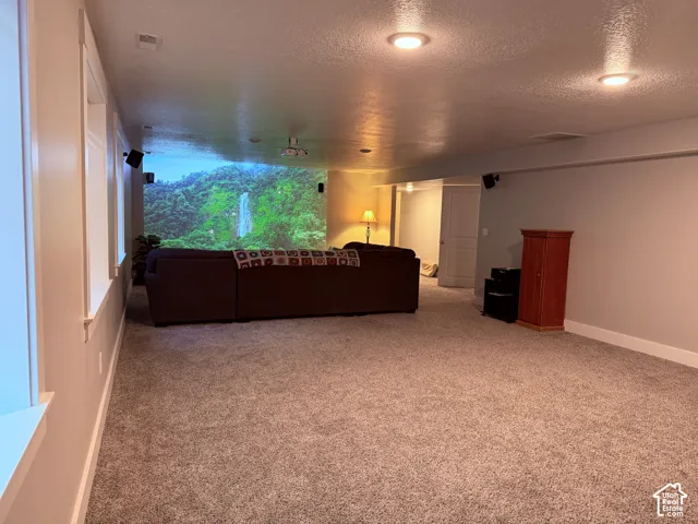 Recessed lighting, wall-mounted projector, wall-mounted audio speakers, neutral carpeting, and solid-core interior doors