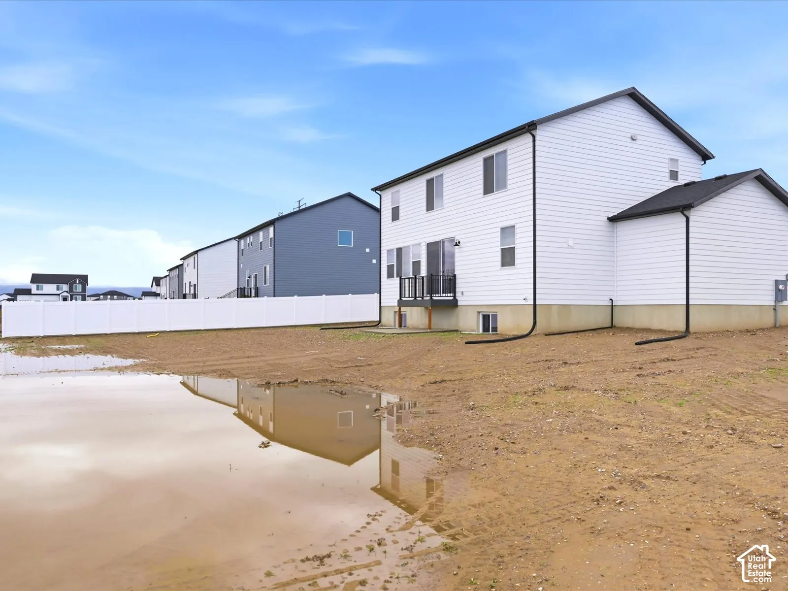 **DISCLAIMER** Fence is only for esthetic view.Two-story residence featuring white horizontal siding, a rear deck with black metal railing, concrete foundation, and a white vinyl privacy fence