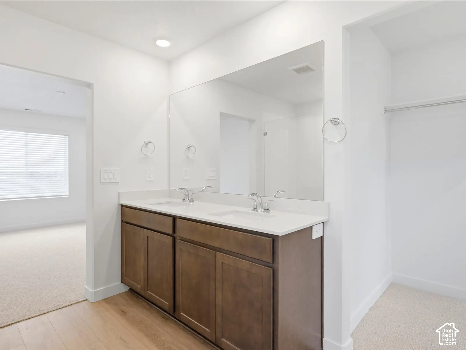 **DISCLAIMER** Interior package may vary. Dual-sink vanity with a solid-surface countertop, full-width mirror, polished chrome fixtures, and built-in wood-finish cabinetry