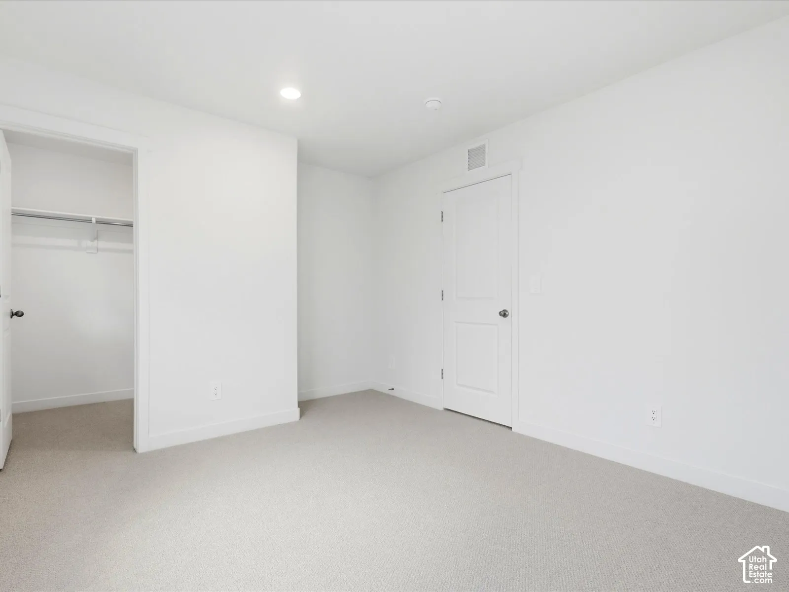 Neutral-toned carpeting, recessed ceiling lighting, two-panel interior doors, and a built-in reach-in closet with integrated shelving