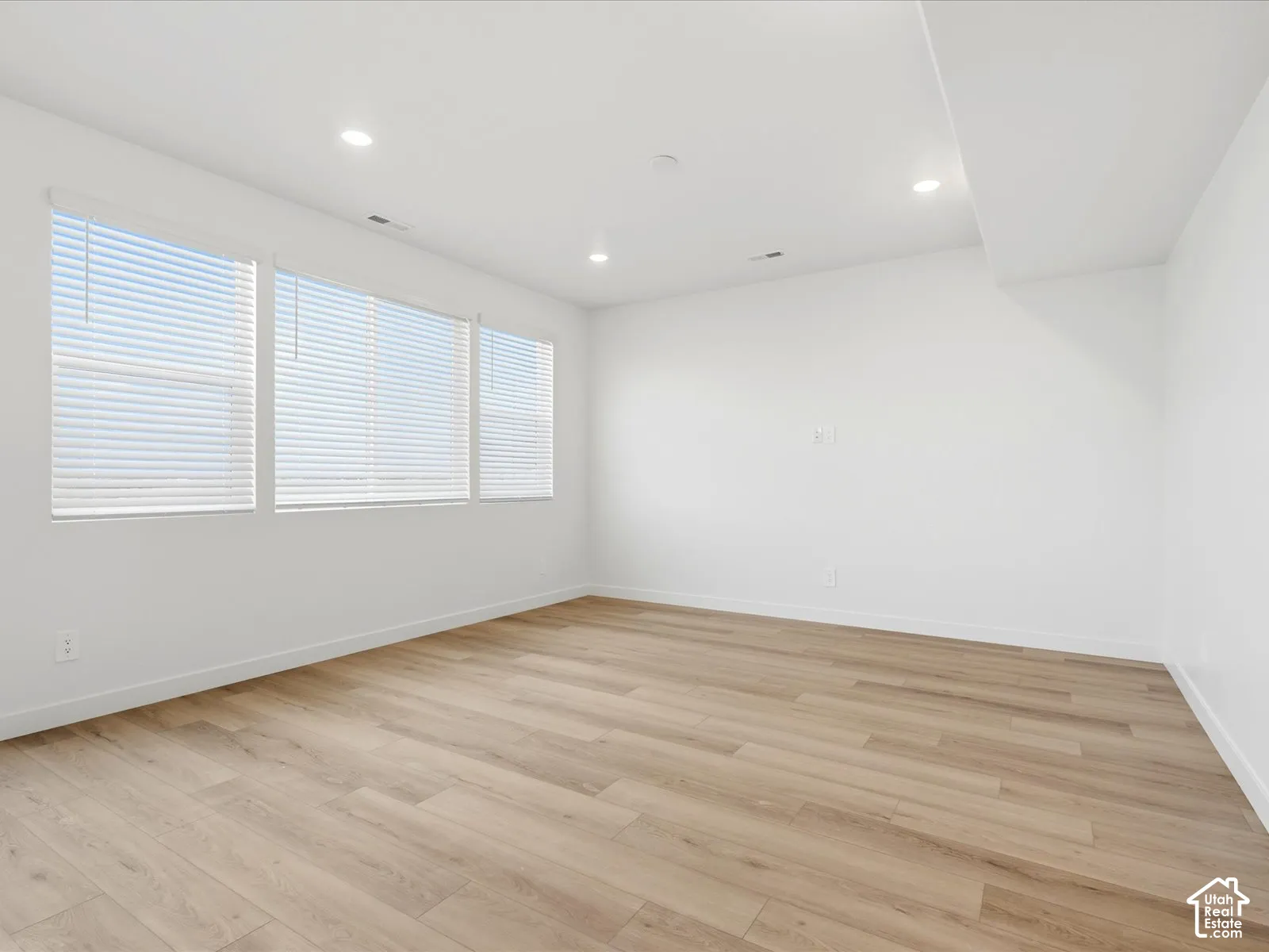 **DISCLAIMER** Interior package may vary. Interior space featuring wood-finish flooring, recessed lighting, and a wall of windows with horizontal blinds