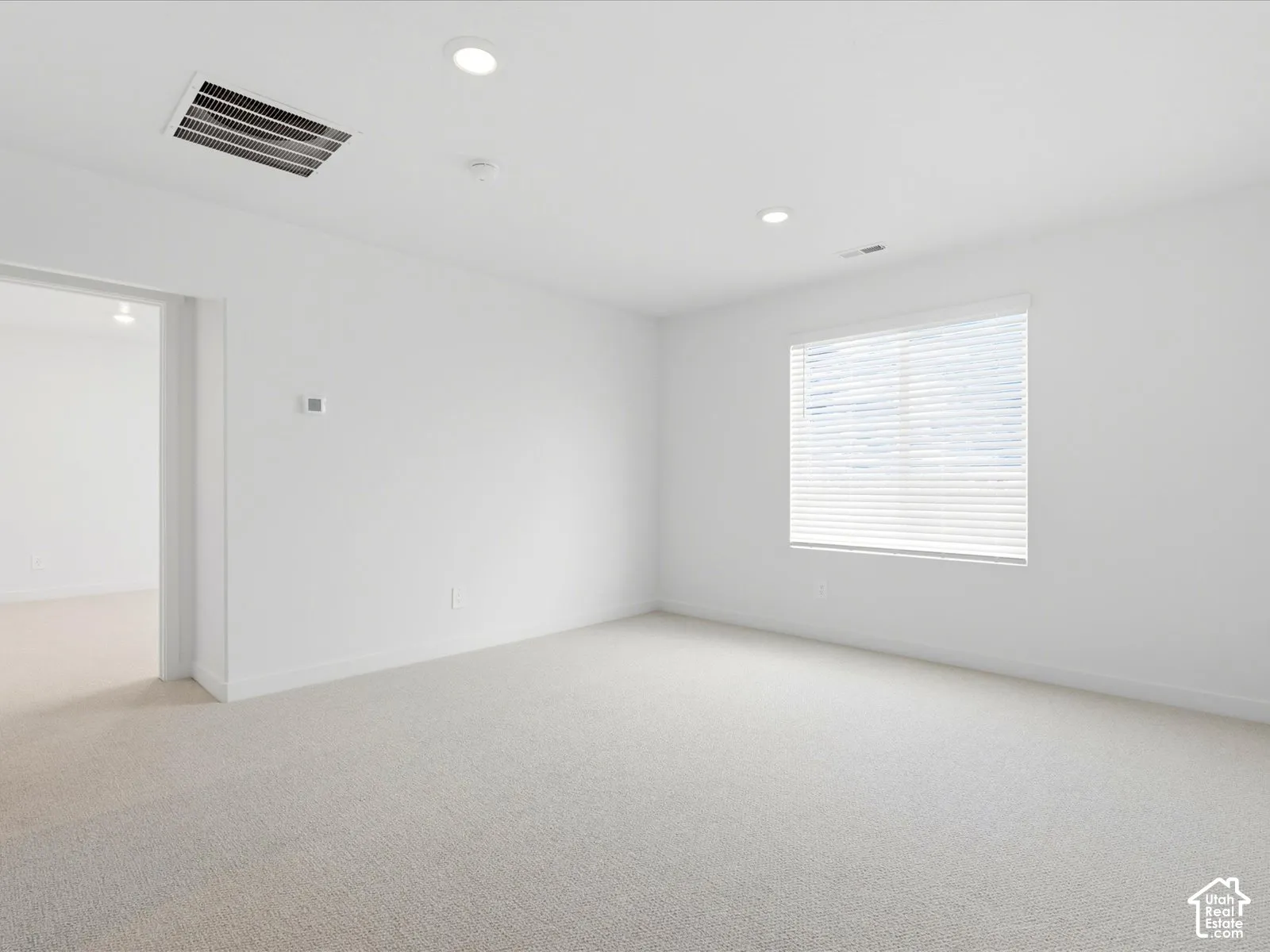 Neutral-toned wall-to-wall carpeting, recessed ceiling lighting, and a window with horizontal blinds