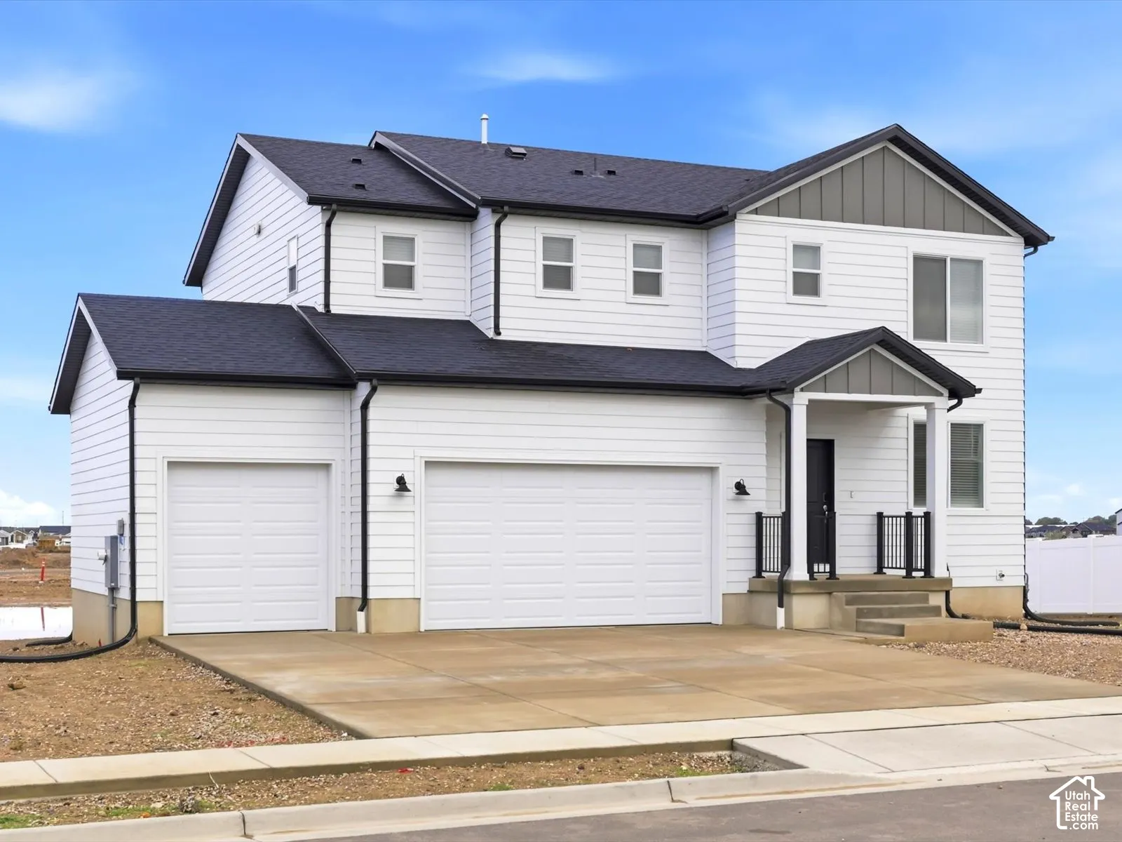 Two-story exterior featuring white horizontal siding, dark-toned roof shingles, vertical panel accents, a concrete driveway, and a three-car garage
