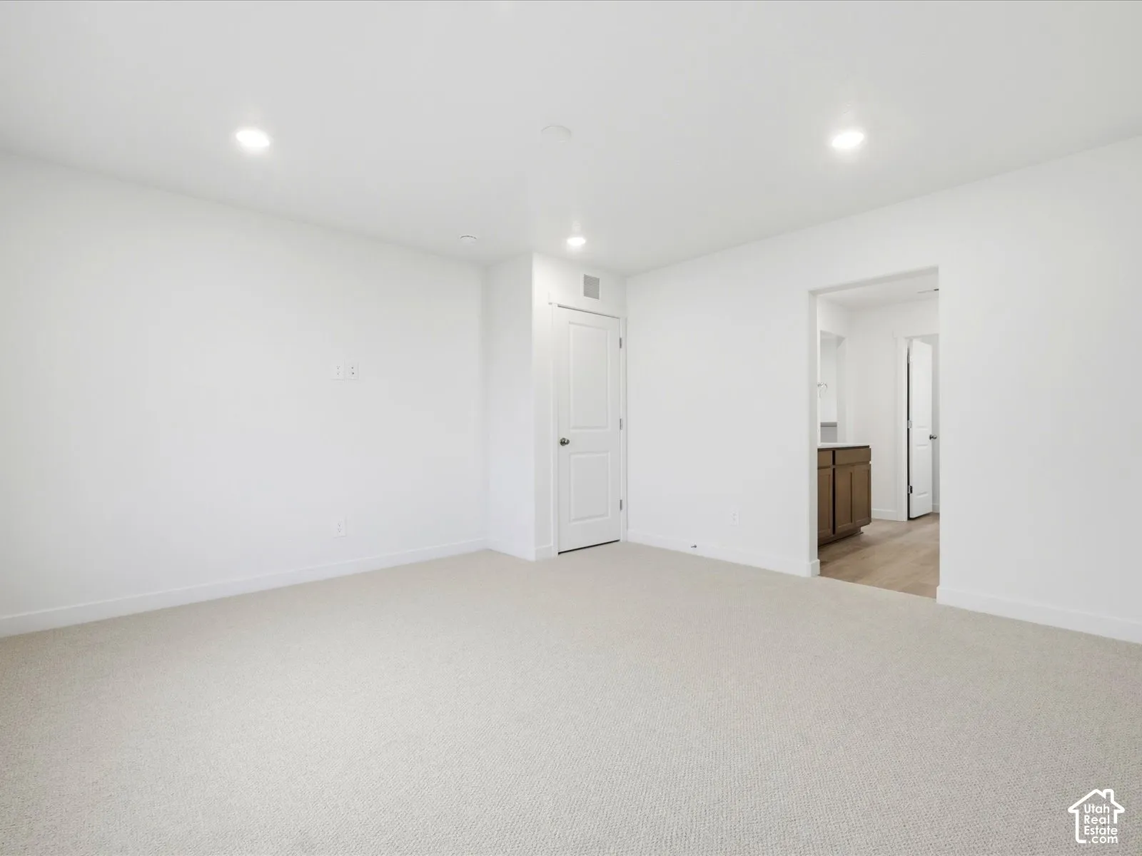 **DISCLAIMER** Interior package may vary. Neutral-toned carpeting, recessed ceiling lighting, and crisp white walls featuring a paneled interior door