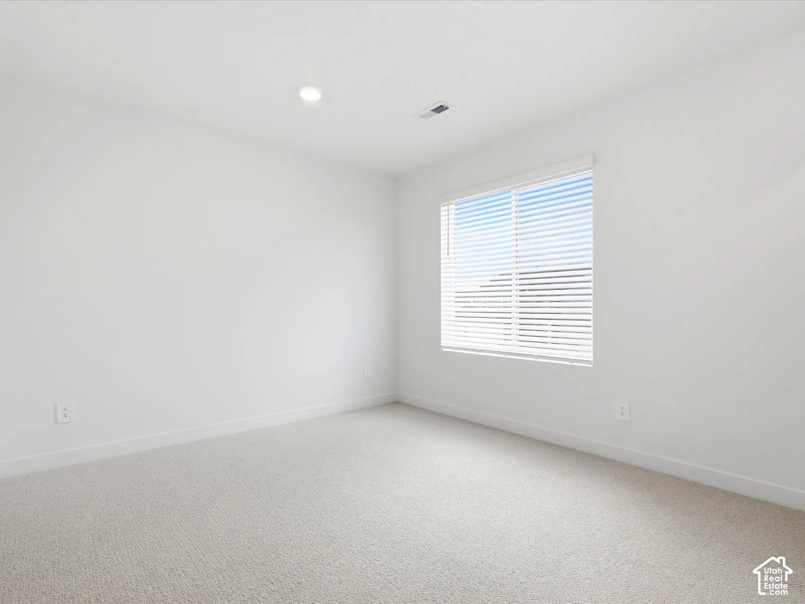 Neutral-toned wall-to-wall carpeting, recessed ceiling lighting, and a single-pane sliding window
