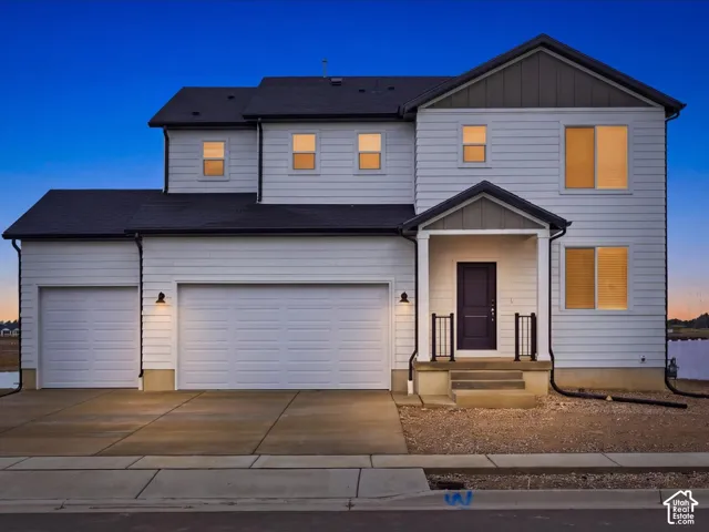 Two-story exterior featuring white horizontal siding, a multi-tone facade with dark gable accents, a three-car garage, and a covered front porch with iron-style railings