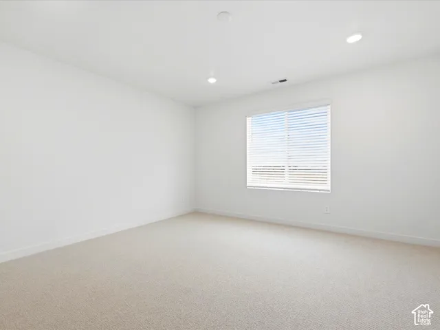 Neutral-toned carpeted flooring, white walls, recessed ceiling lighting, and a window with horizontal blinds