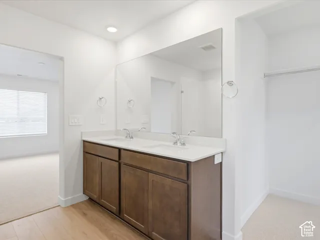 **DISCLAIMER** Interior package may vary. Dual-sink vanity with a solid-surface countertop, full-width mirror, polished chrome fixtures, and built-in wood-finish cabinetry