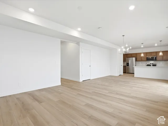 **DISCLAIMER** Interior package may vary. Open-concept interior featuring wood-finish flooring, recessed lighting, a kitchen island with pendant lighting, and cabinetry with stainless steel appliances