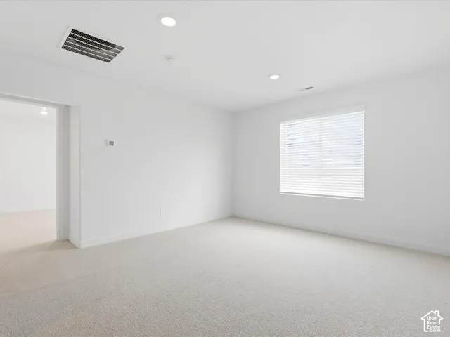 Neutral-toned wall-to-wall carpeting, recessed ceiling lighting, and a window with horizontal blinds