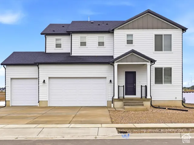 Two-story residence featuring white horizontal siding, dark shingle roofing, a three-car garage, and a covered front porch with metal railing