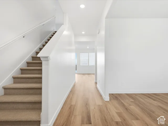 **DISCLAIMER** Interior package may vary. Interior featuring wood-finish flooring, staircase with carpeted treads, white wall finishes, recessed ceiling lighting, and windows with white blinds