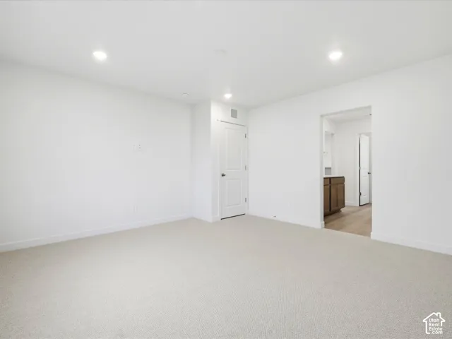 **DISCLAIMER** Interior package may vary. Neutral-toned carpeting, recessed ceiling lighting, and crisp white walls featuring a paneled interior door