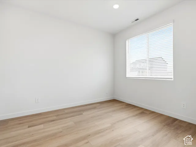**DISCLAIMER** Interior package may vary. Neutral-toned interior room featuring wood-finish flooring, white walls, recessed ceiling lighting, and a window with horizontal blinds