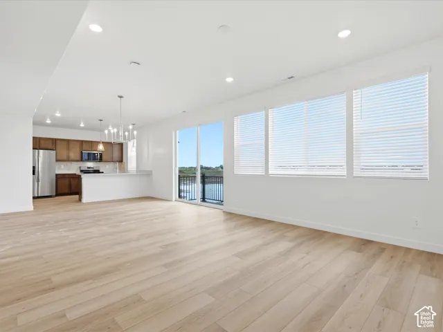 **DISCLAIMER** Interior package may vary. Open-concept interior featuring light wood-finish flooring, recessed lighting, expansive multi-pane windows, and a kitchen equipped with wood cabinetry and a peninsula counter
