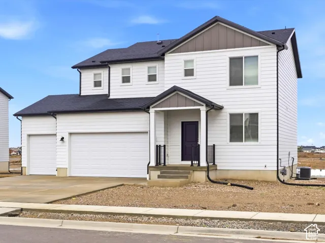 Two-story exterior featuring white horizontal siding, contrasting dark-toned roof shingles, a covered entryway with a gable roof, and a three-car garage