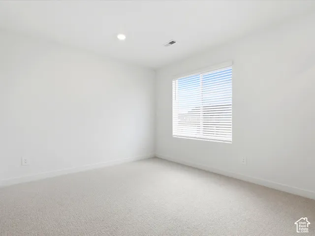 Neutral-toned wall-to-wall carpeting, recessed ceiling lighting, and a single-pane sliding window