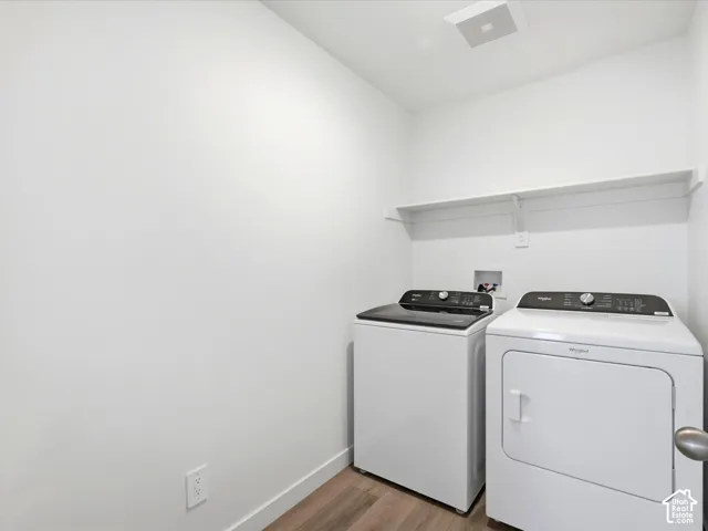 Laundry area featuring wood-finish flooring, white walls, and a wall-mounted shelving unit