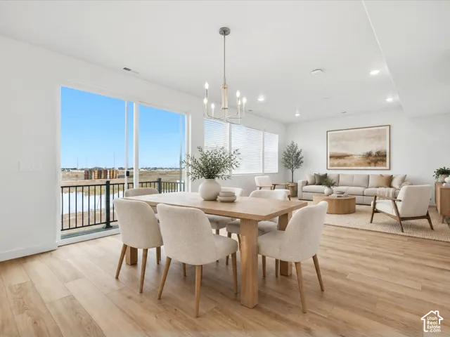 **DISCLAIMER** Interior package may vary. Open-concept space featuring wood-finish flooring, recessed lighting, a modern multi-arm chandelier, and sliding glass doors with a metal balcony railing
