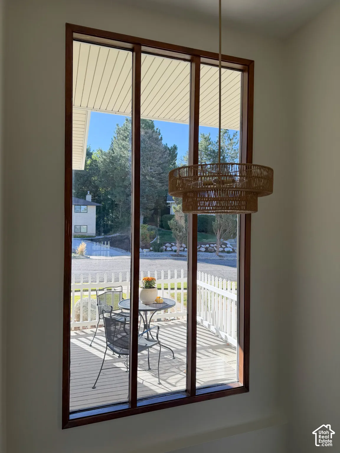Floor-to-ceiling multi-pane window with wood trim, featuring a tiered woven pendant light fixture