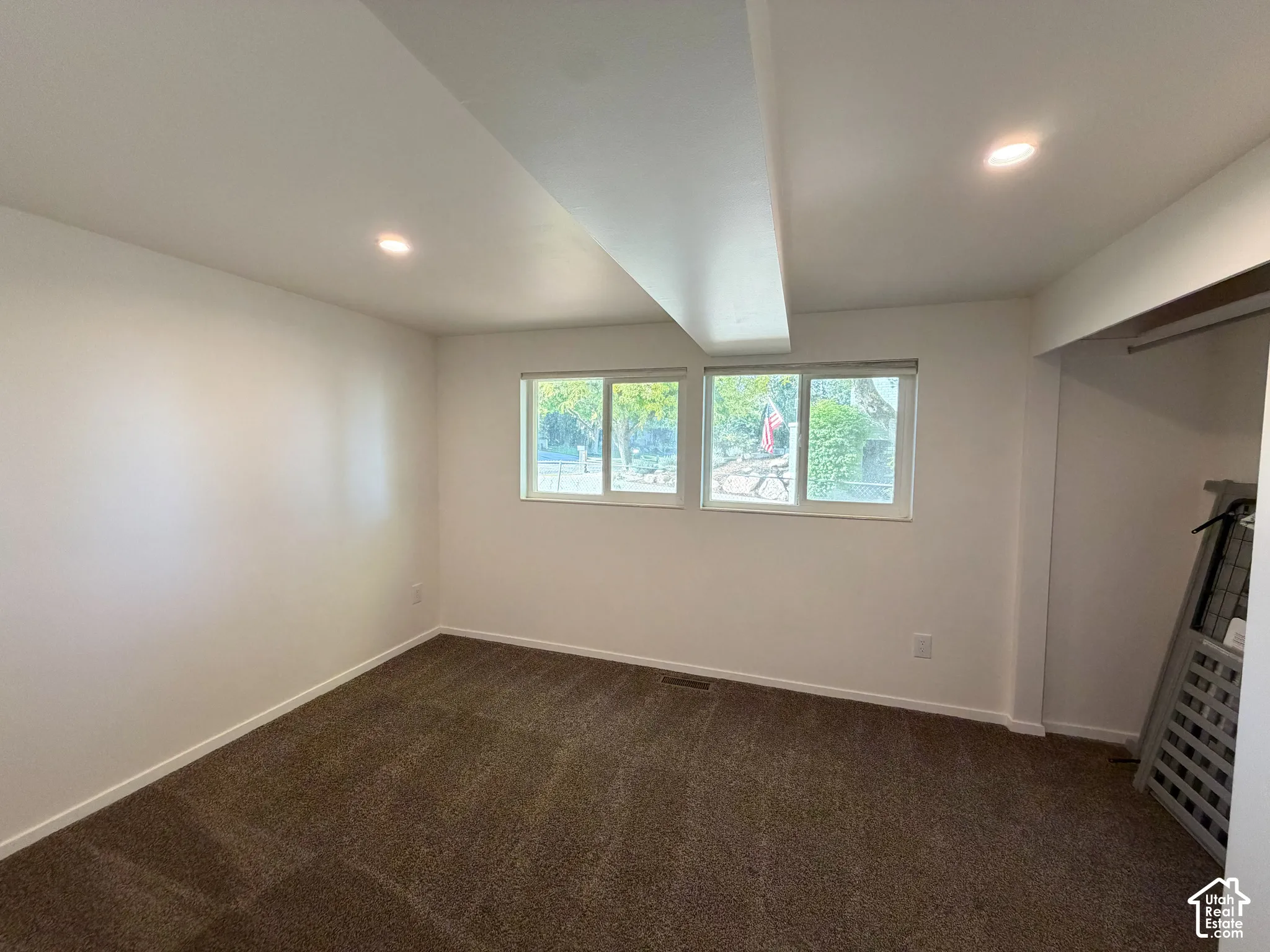 Interior space featuring wall-to-wall carpeting, dual horizontal sliding windows, recessed ceiling lighting, and built-in closet storage