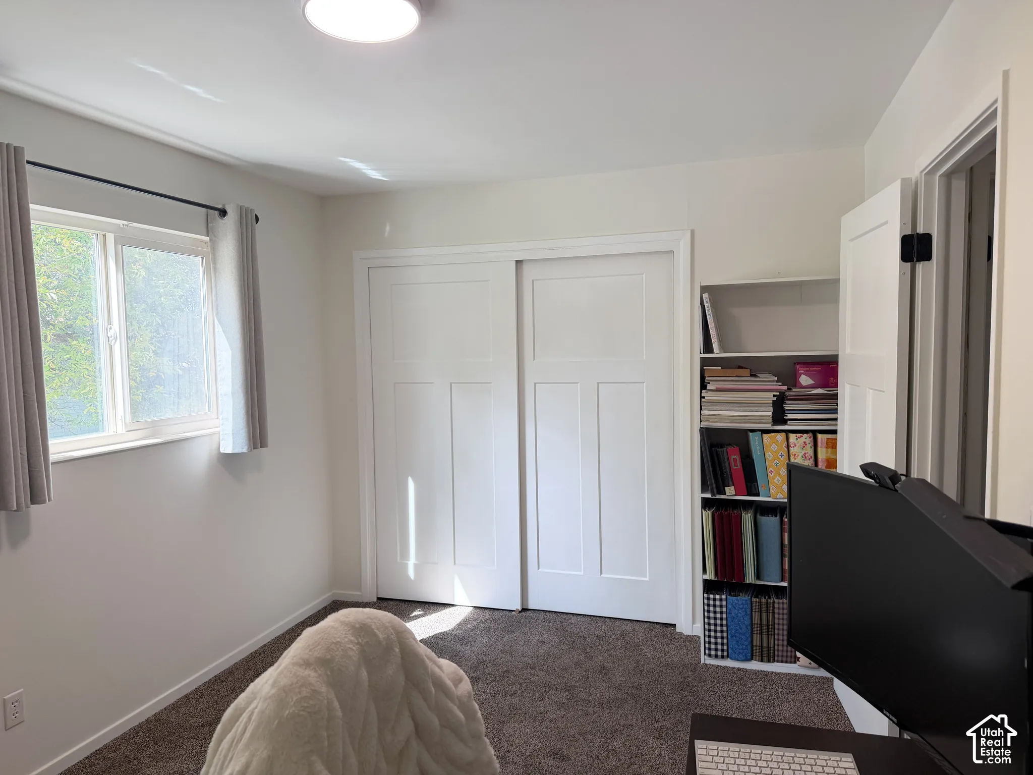 Neutral wall palette with carpeted flooring, sliding-panel closet doors, and built-in shelving