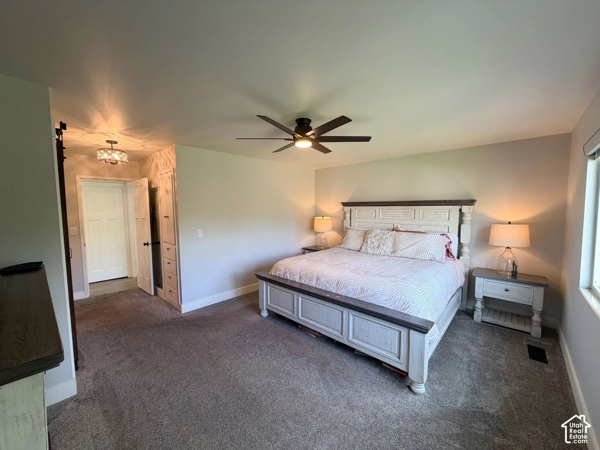 Neutral-toned carpeted flooring, built-in cabinetry, ceiling fan with integrated lighting, and multi-panel interior doors