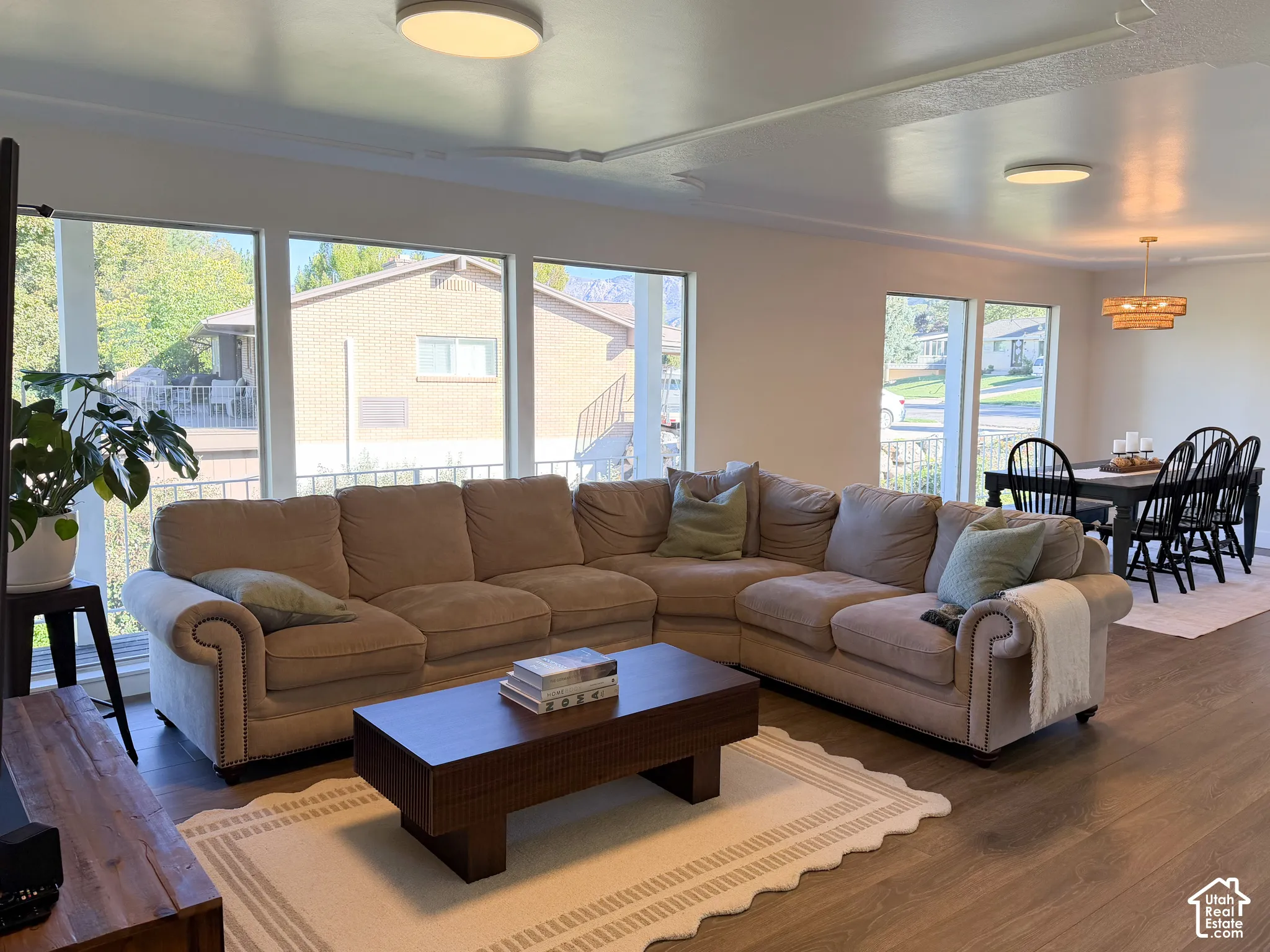 Open-concept living space featuring wood-finish flooring, floor-to-ceiling windows, and modern flush-mount lighting