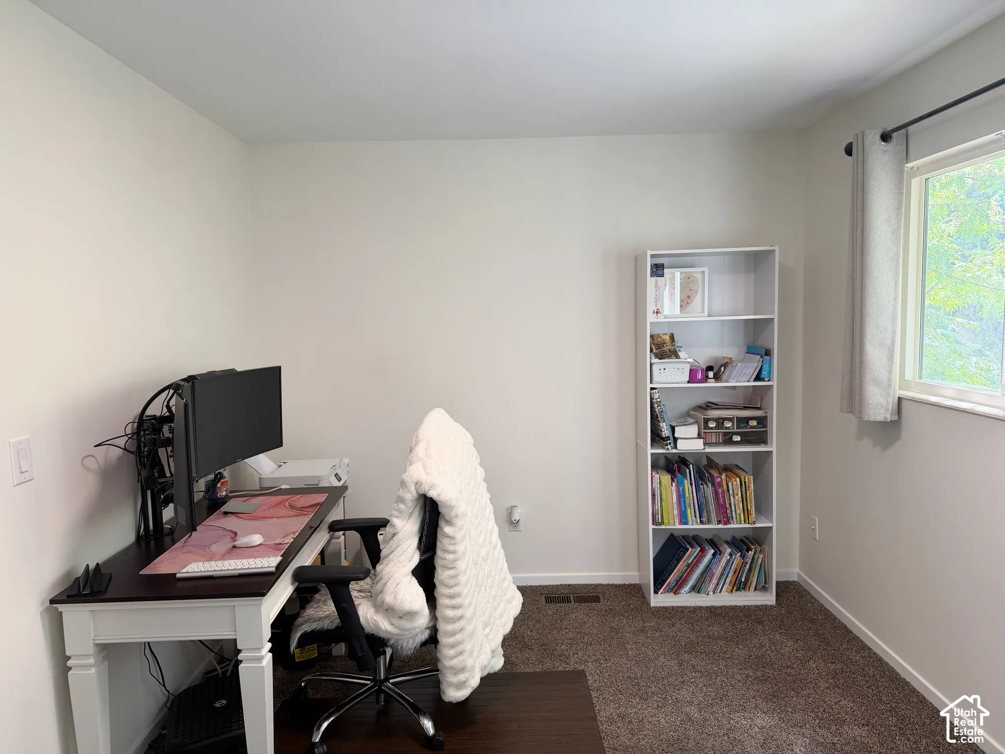 Neutral-toned room featuring plush wall-to-wall carpeting and a window with a horizontal frame