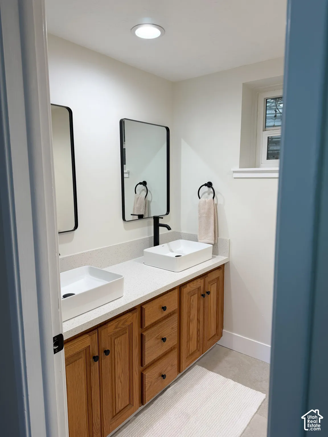 Dual-sink vanity with rectangular vessel basins, quartz-style countertops, wood cabinetry, and matte black hardware