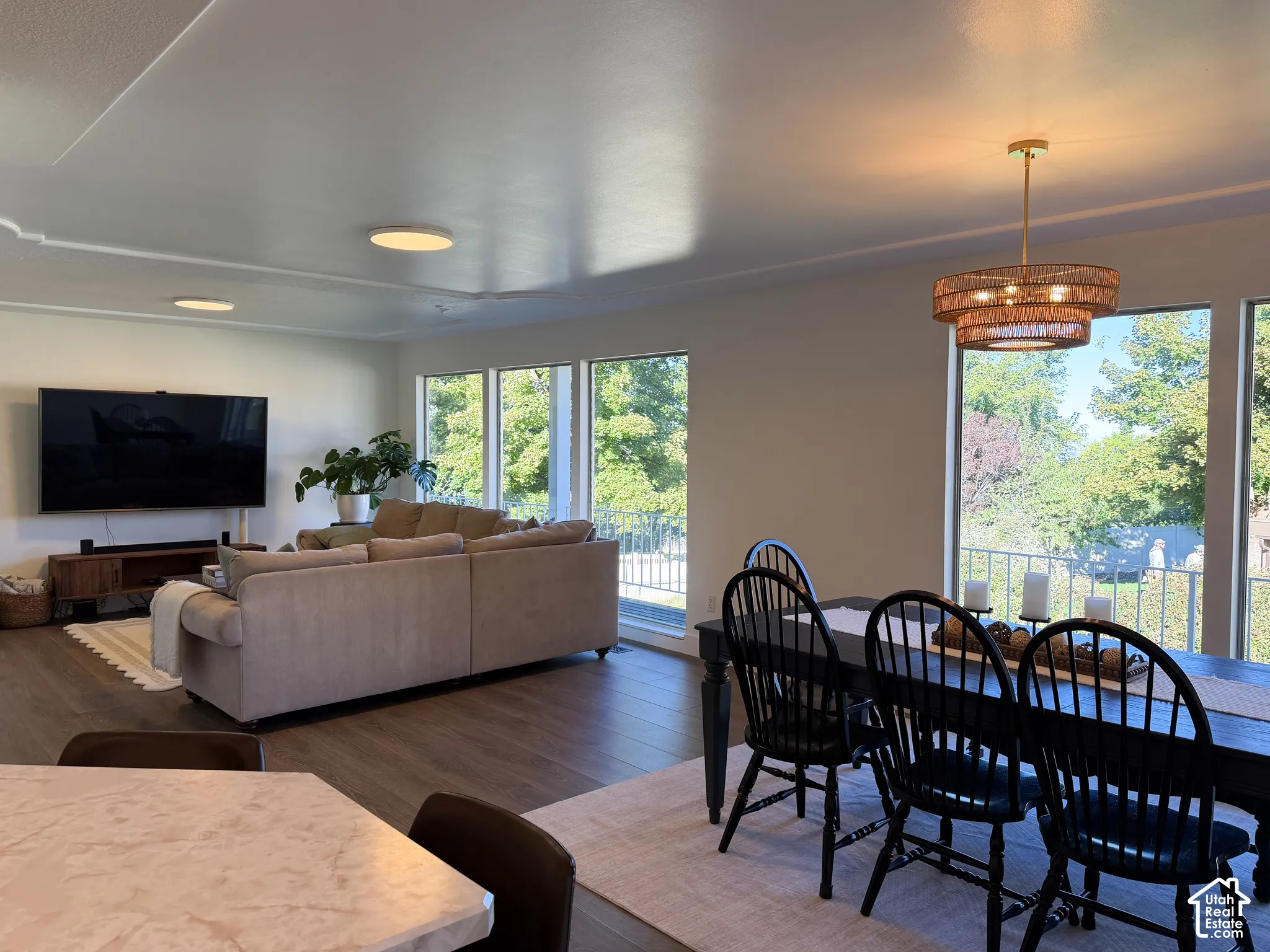Spacious open-concept interior featuring wood-finish flooring, recessed lighting, expansive multi-panel windows, and a tiered metal chandelier