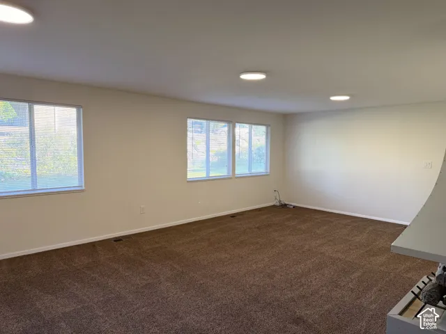 Neutral-toned walls, carpeting, multiple windows, and flush-mount ceiling lighting