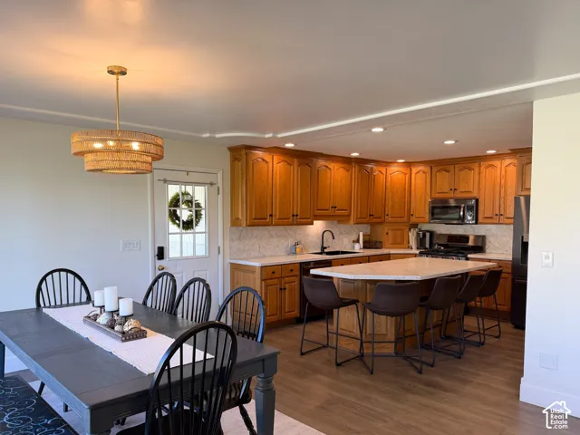 Kitchen featuring wood cabinetry, stone-finish countertops, a central island with bar seating, and recessed lighting