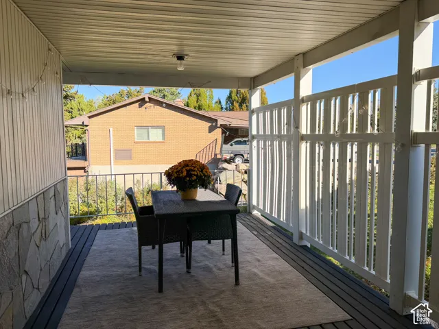 Covered deck featuring wood-finish decking, stone masonry siding, and a white privacy screen