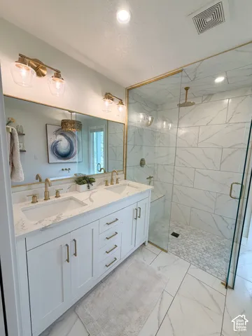 Double vanity featuring white cabinetry, stone-patterned countertops, and brass-finish hardware