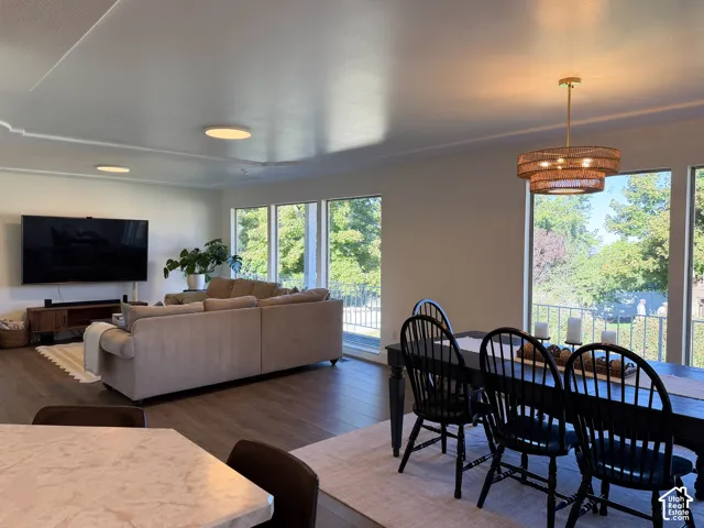 Spacious open-concept interior featuring wood-finish flooring, recessed lighting, expansive multi-panel windows, and a tiered metal chandelier