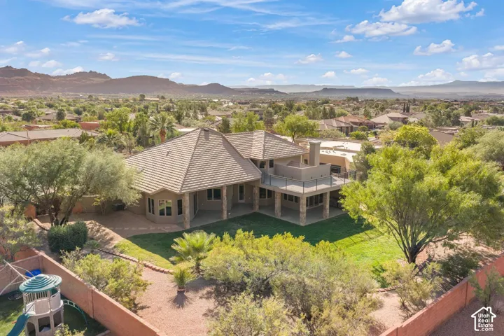 Multi-level exterior featuring a stone-clad foundation, a tile roof, an expansive upper-level balcony with metal railing, a covered patio, and desert-inspired landscaping