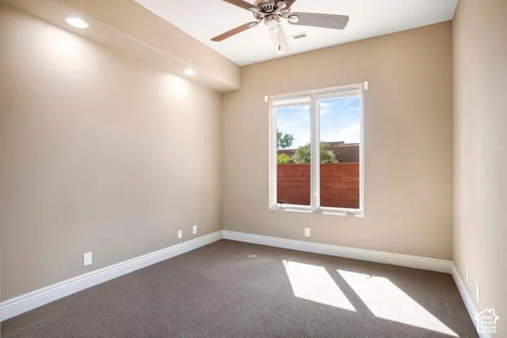Room featuring neutral carpeting, a vaulted ceiling, recessed lighting, a ceiling fan, and a window with exterior brick wall scenery