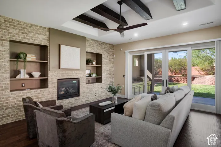 Living area featuring a floor-to-ceiling brick fireplace with integrated shelving, dark wood-finish ceiling beams, and glass-paned double doors providing access to the exterior