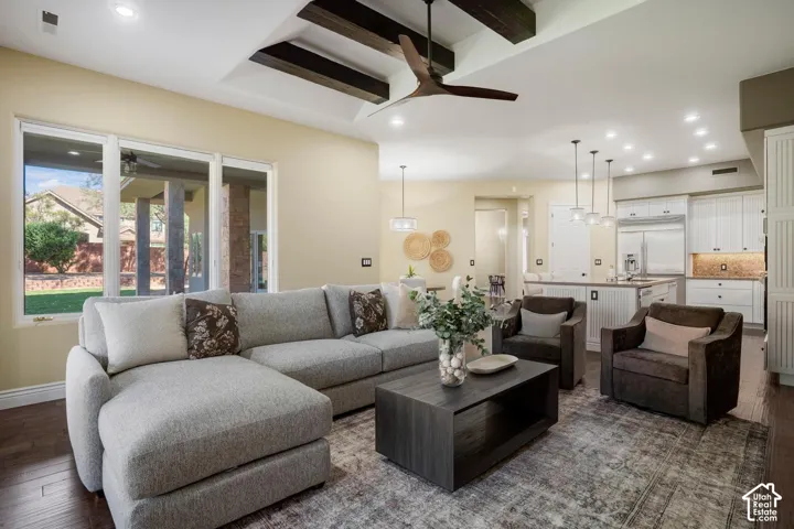 Living area featuring a vaulted ceiling with exposed wooden beams, recessed lighting, wood-finish flooring, and expansive windows with exterior access