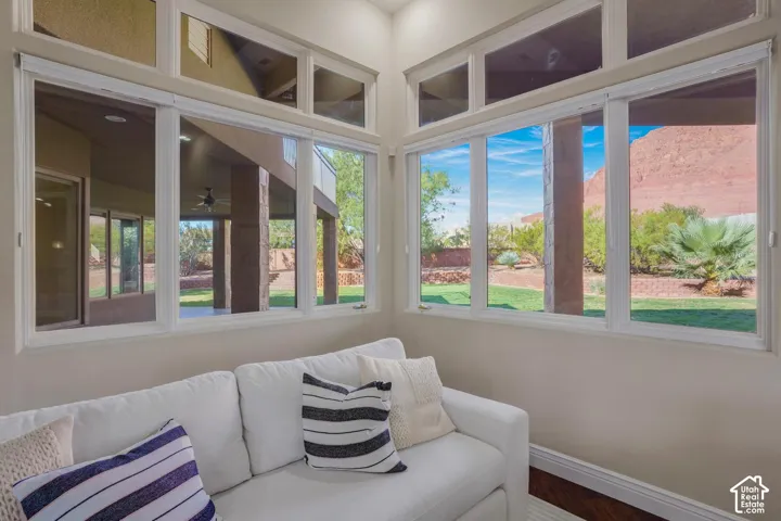 Corner room featuring oversized windows with transom accents, wood-finish flooring, and direct sightlines to the outdoor covered patio and sandstone rock formations