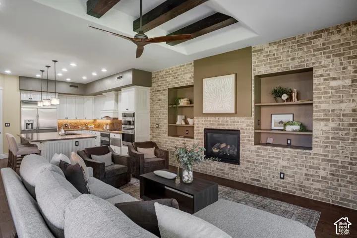 Open-concept area featuring exposed wooden ceiling beams, brick masonry wall, built-in recessed shelving, integrated fireplace, and recessed lighting