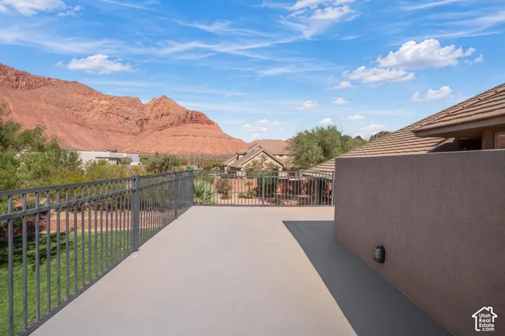 Outdoor balcony featuring a smooth surface floor, dark metal railing, and a mountain backdrop