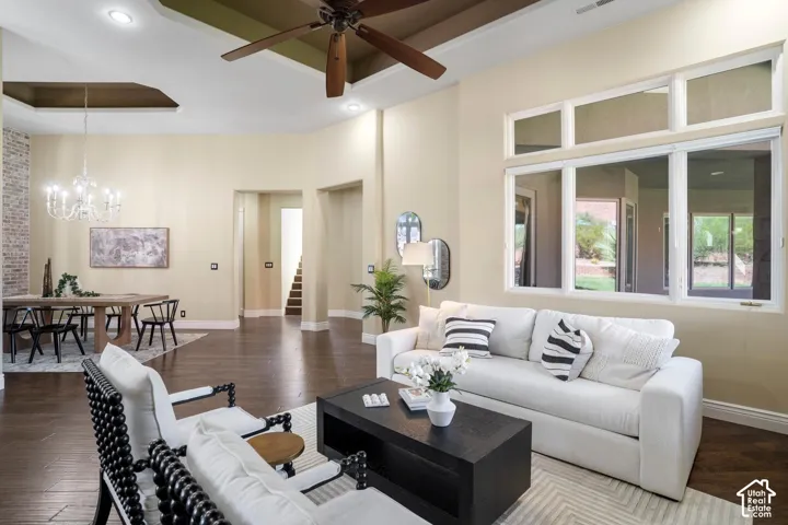 High-ceiling living area featuring a recessed tray ceiling, wood-finish flooring, a multi-pane picture window, and a decorative brick accent wall