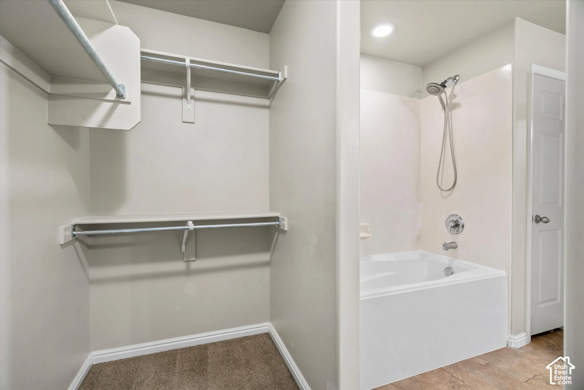 Walk-in closet featuring multi-level built-in shelving and hanging rods, accompanied by a bathroom with a soaking tub and wall-mounted shower head